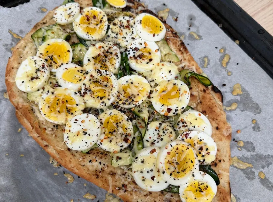 Homemade protein pizza topped with courgette and sliced boiled eggs